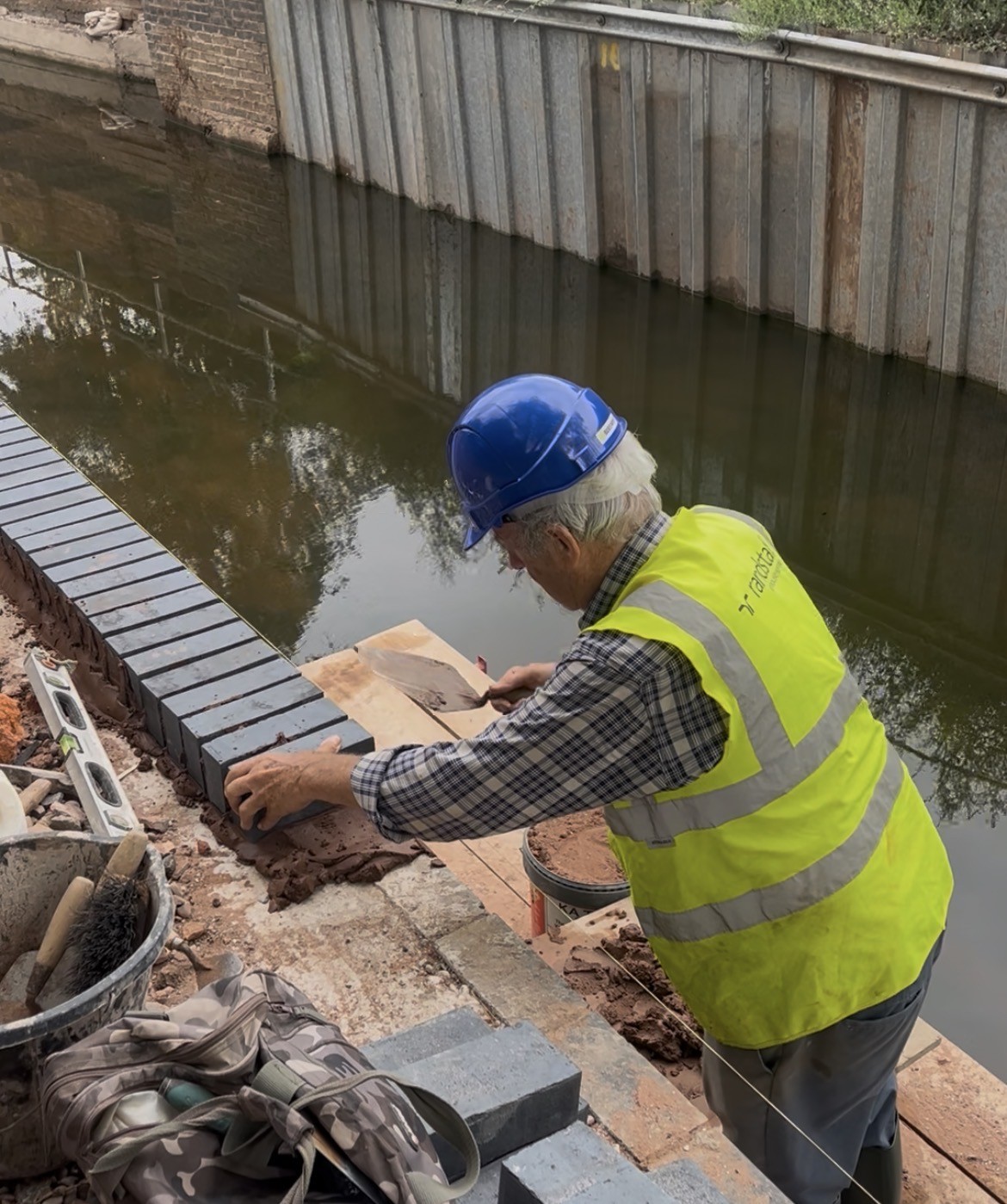 A volunteer laying bricks beside the restored Lichfield Canal at Gallows Reach
